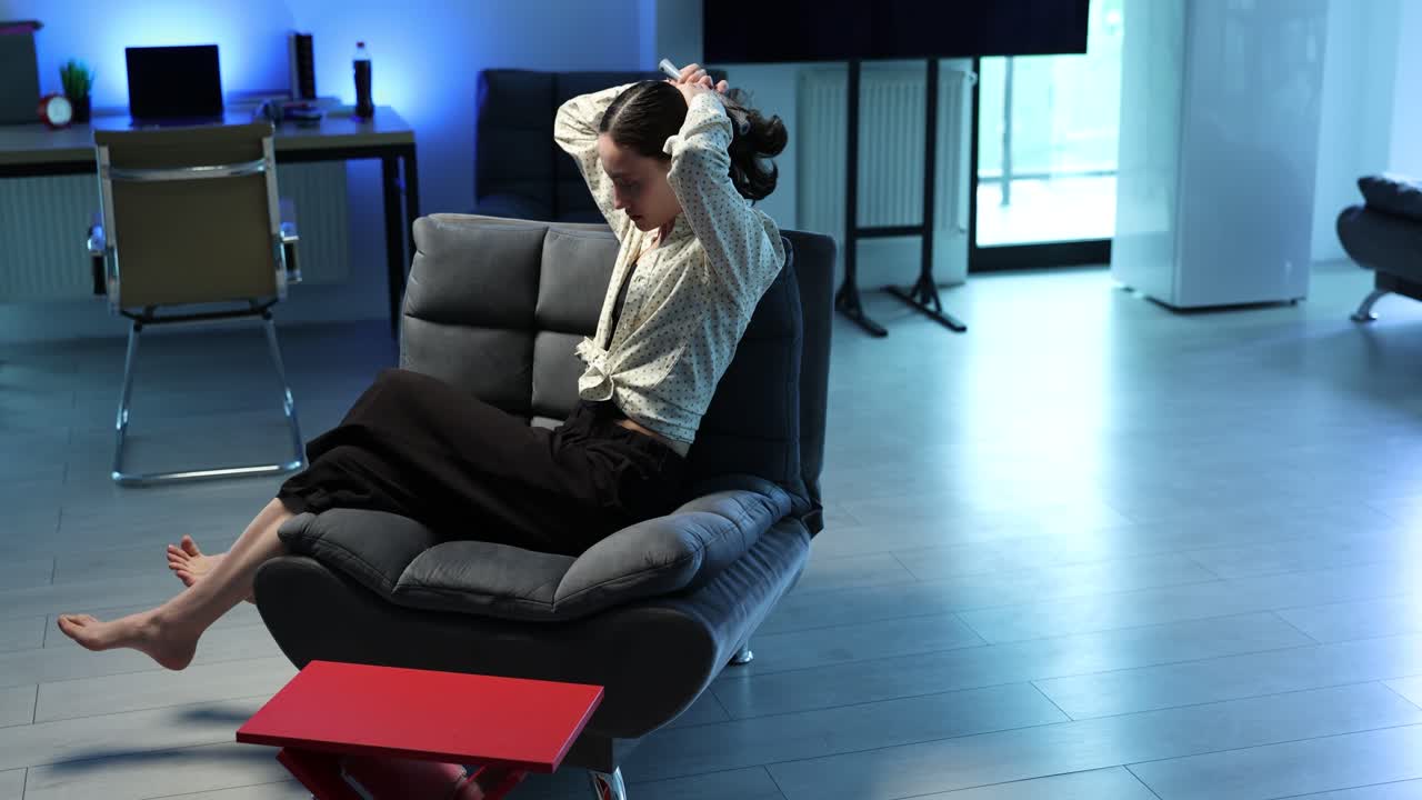 Woman relaxing and brushing her hair in a living room