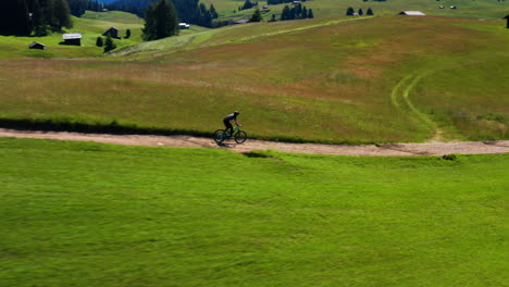 man on bike traveling through alpe di siusi dolomite plateau in italy