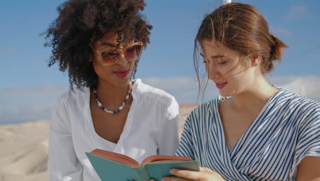 laughing women reading book on beach closeup. love partners enjoying summer