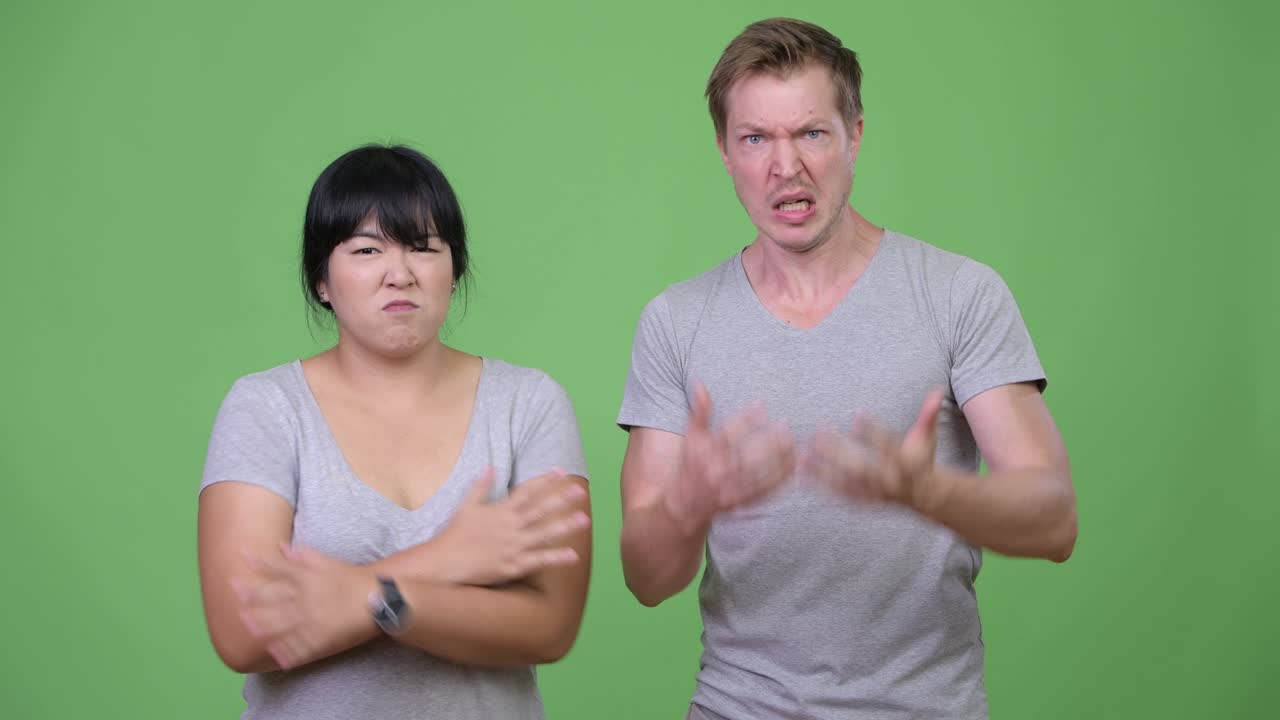 Young multi-ethnic couple angrily talking to camera