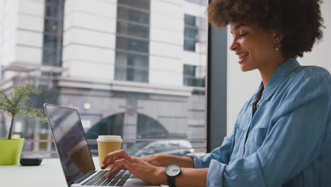 businesswoman in modern office working on laptop and answering mobile phone