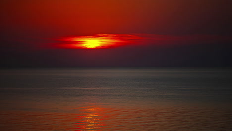 hermoso sol rojo poniéndose en el horizonte más allá de las olas tranquilas - hiperlapso