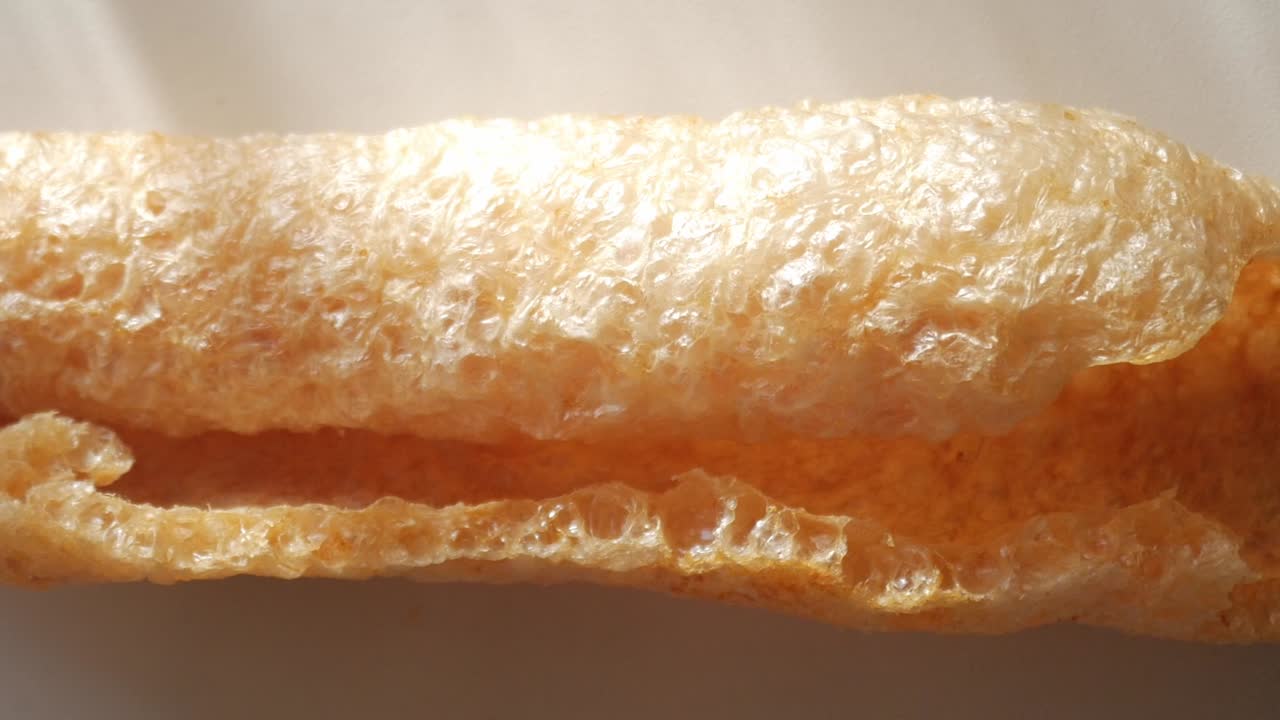 Pork rind close-up showing crispy texture and golden color, concept of snack food