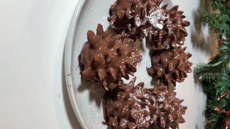 vertical - sprinkling powdered sugar on chocolate pinecone brownies