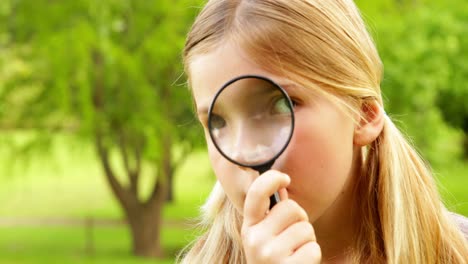 cute little girl using magnifying glass in park