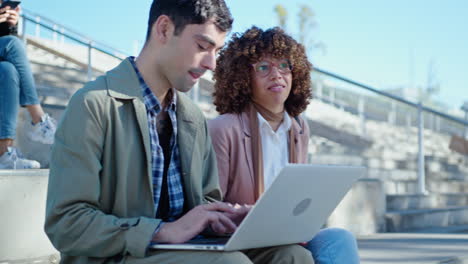 Young Man and Woman Working with Laptop and Talking Outdoors