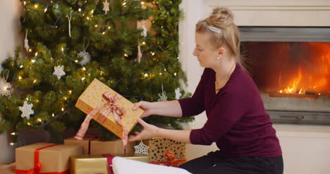 woman positioning christmas presents under the tree 1