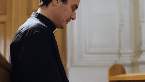 priest sitting in a bench indoors