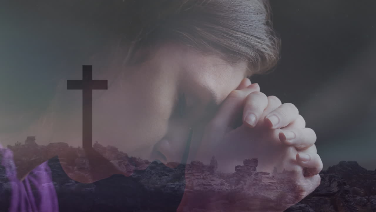 Praying with hands clasped, woman in front of cross and landscape background