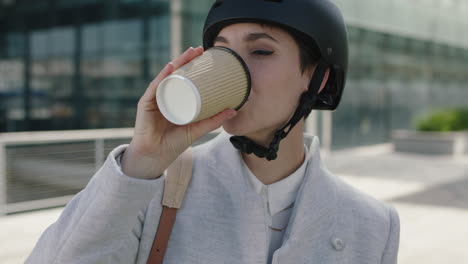 close up portrait of beautiful young business woman intern wearing safety helmet drinking coffee ready to leave work