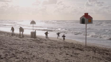 Silhouette-Of-Children-Playing-On-Beach-At-Sunset,-Belgium---slow-motion,-wide