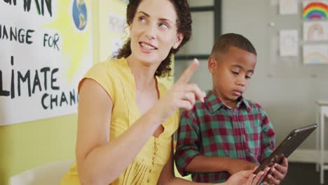 video of happy caucasian female teacher and african american boy studying ecology in classroom