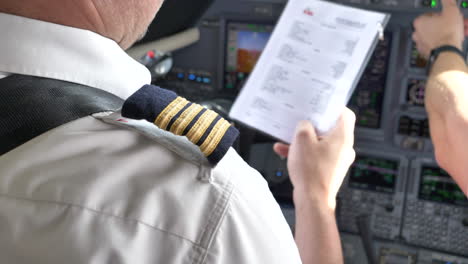 Pilotos-De-Líneas-Aéreas-En-Uniforme,-Cerrar-Lista-De-Verificación-De-Vuelo-De-Cabina,-4k