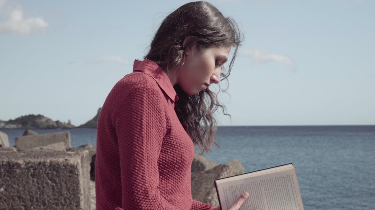 niña leyendo un libro cerca del mar
