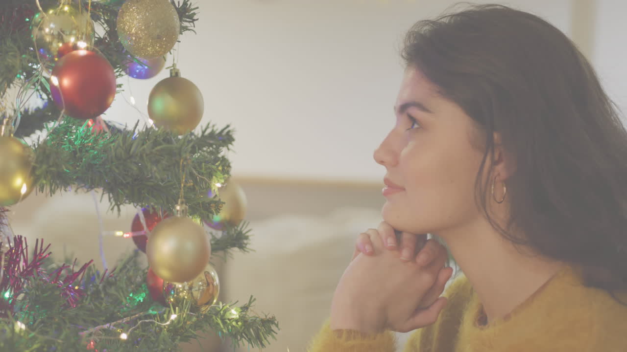 animación de banner de texto de feliz navidad sobre una mujer caucásica mirando un árbol de navidad decorado