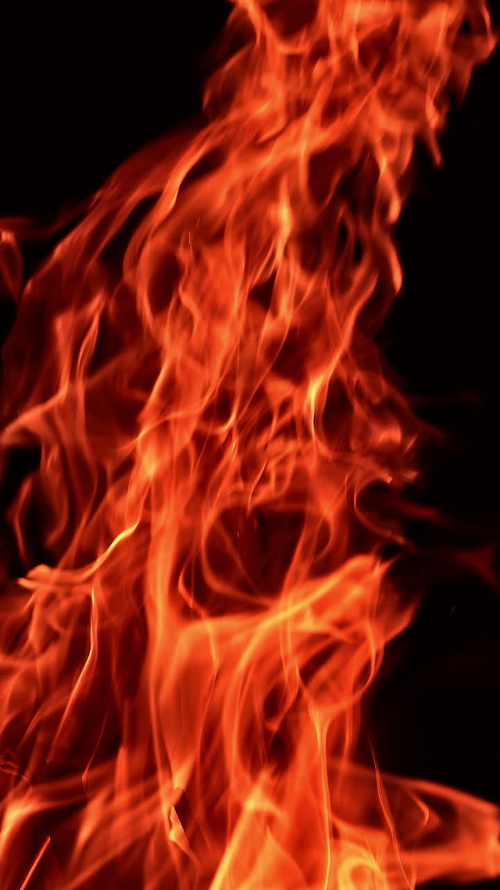 Beautiful flame of burning campfire rising up. Fire isolated on black backdrop. Close up. Vertical video