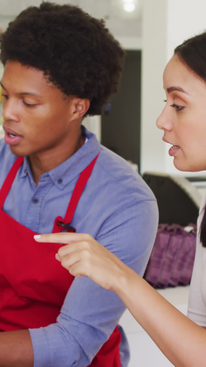 video de una mujer propietaria y un camarero trabajando con una computadora portátil en una cafetería