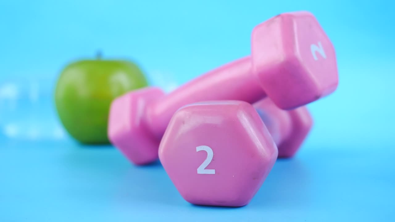 Lyserøde håndvægte og et æble