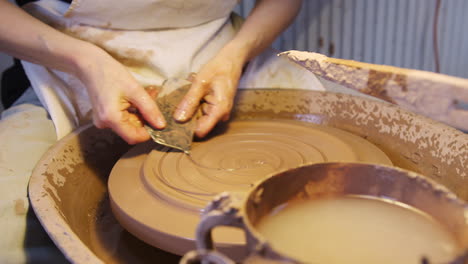 Close-Up-Of-Male-Potter-Putting-Design-In-Clay-On-Pottery-Wheel-In-Ceramics-Studio