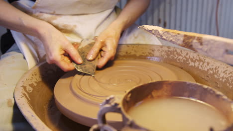 close up of male potter putting design in clay on pottery wheel in ceramics studio