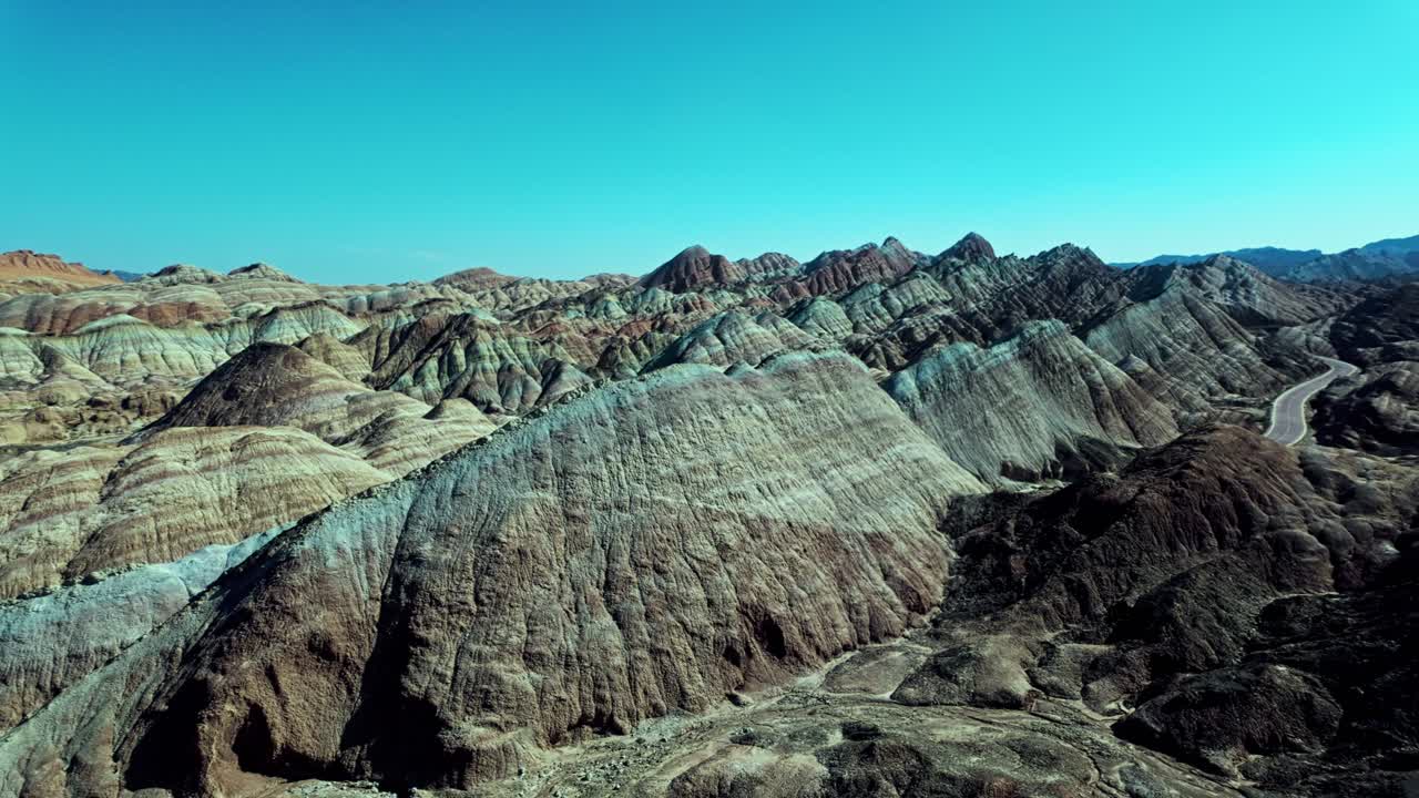 Zhangye, Gansu Province, China - Softly Layered, Wave-Like Hills Stretch Across the Landscape in Muted Tones Under a Cloudless Blue Sky - Pan Shot