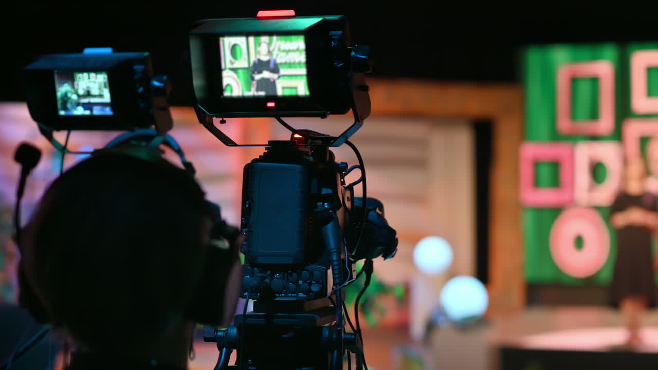 Cameraman filming a television talk show on a professional camera. Video production backstage in a dark studio