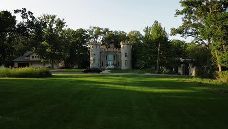 Drone-Flying-Over-Green-Yard-Towards-Stunning-Design-Guest-Castle,-Chicago-City