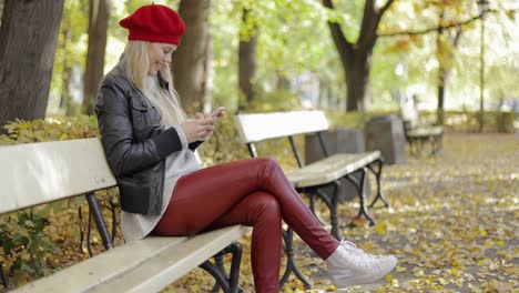 Lächelnde-Frau-In-Baskenmütze-Mit-Smartphone