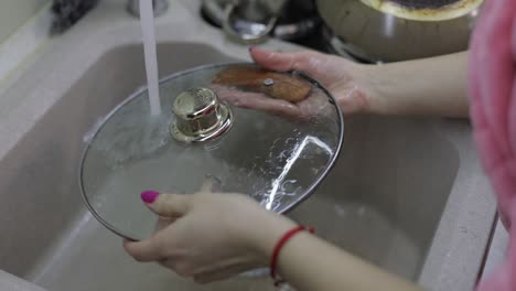 mujer lavando platos en la cocina. primer plano de la mano de la mujer