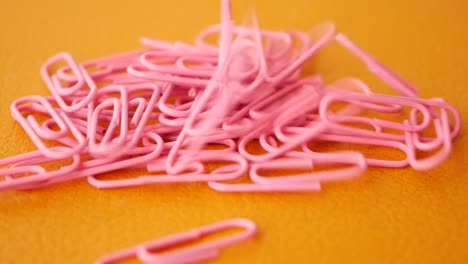pile of pink paperclips on orange surface