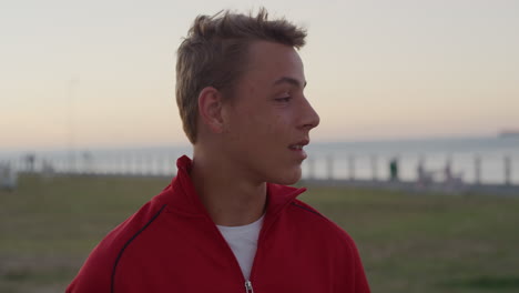 portrait young teenage boy looking around smiling enjoying relaxed day on seaside park at sunset distracted caucasian kid slow motion