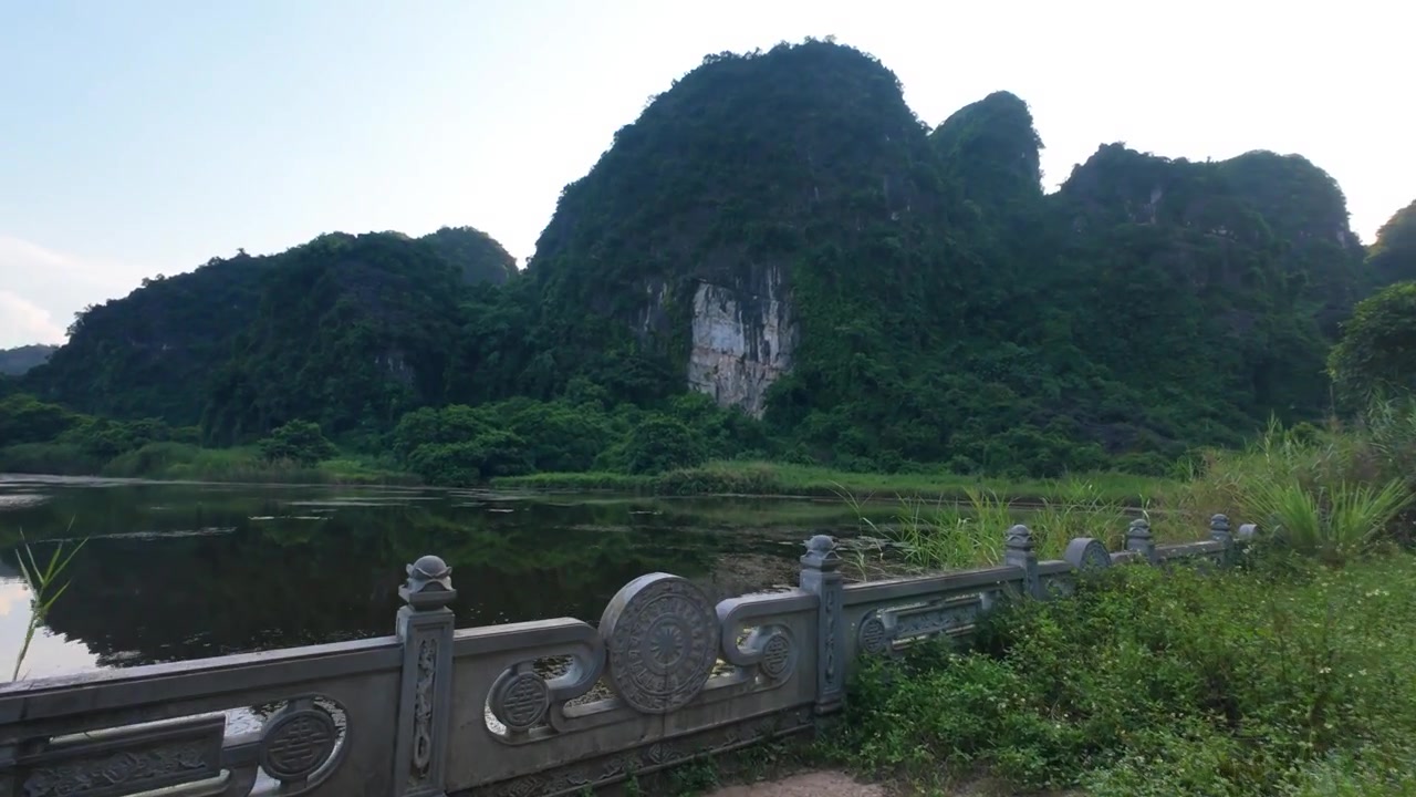 Đi bộ qua những cột đá của Đền Voi hướng về một hồ nước thơ mộng được bao quanh bởi núi đá vôi ở Ninh Bình, Việt Nam