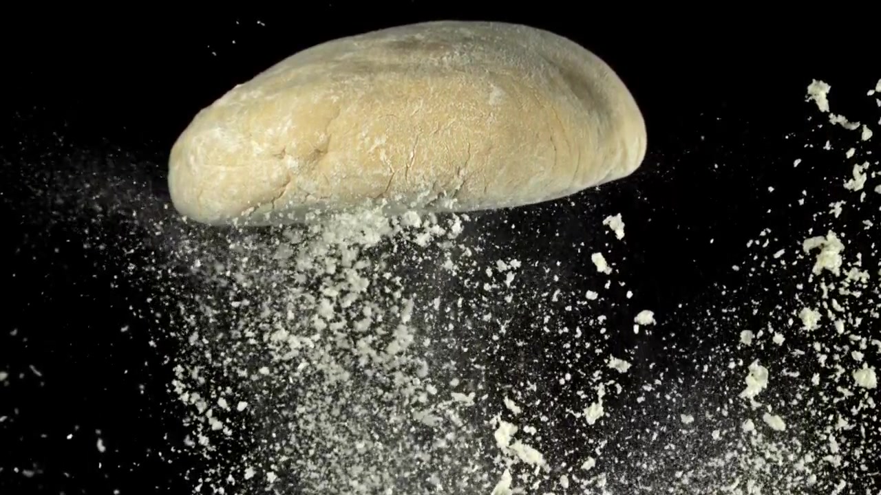Fresh Dough with Flour Falling in Slow Motion on Black Background
