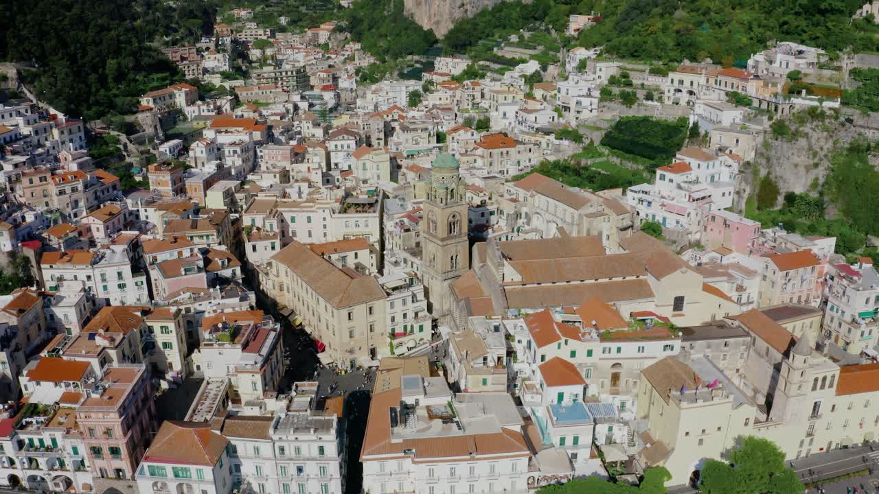 Vista aerea con drone della città di Amalfi con la storica cattedrale e edifici dai toni bianchi sotto drammatiche scogliere montane. La destinazione di viaggio più popolare in Italia.