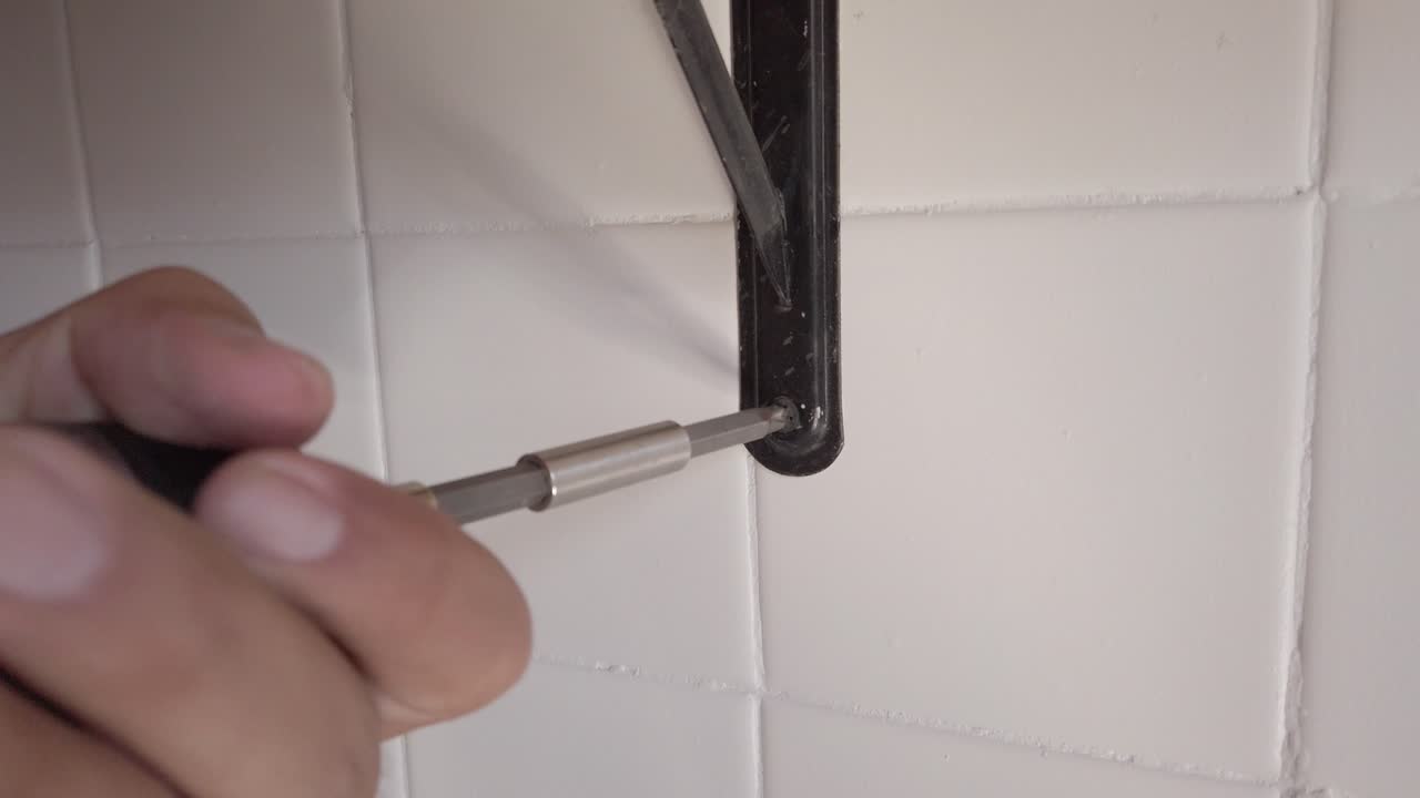 Close-Up of Hand Using Power Drill to Install Bracket on Tiled Wall