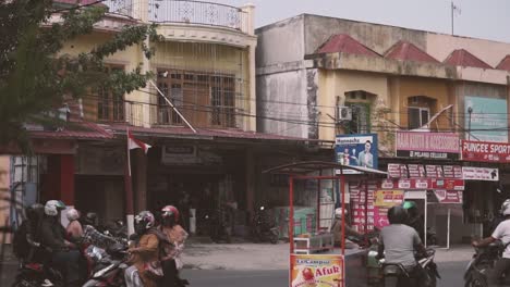asian city street with lots of traffic consisting of scooters and cars.