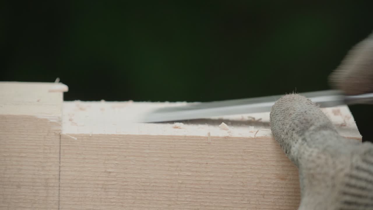 Falegname che usa uno scalpello su un pezzo di legno - Primo piano di mani guantate