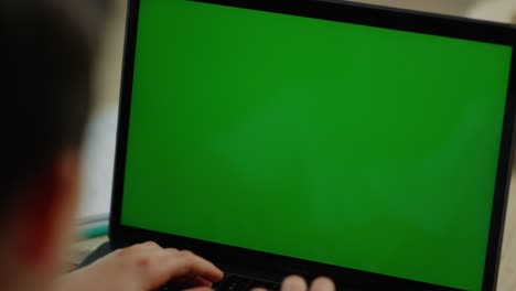 boy typing on computer at home. schoolboy looking laptop screen inside.