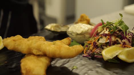 slowmo - chef finishing dish fried shrimps, fish, chicken, green salad, oysters, dressing and gravy - close up