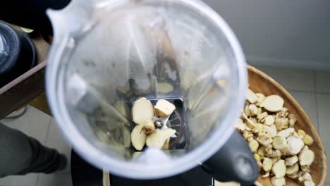 Adding-freshly-cut-ginger-into-a-blender-to-create-a-ginger-root-beverage