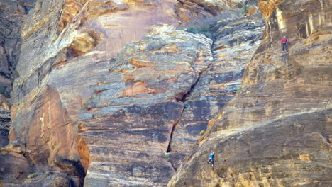 telephoto shot of two rock climbers climbing up a cliff at zion national park, utah, united states