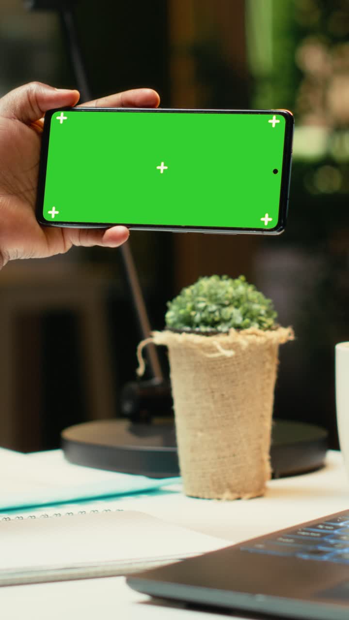 Vertical Video Green screen on smartphone next to black woman checking financial data