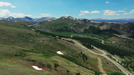 Antena-Sobre-Los-árboles-Y-Colinas-De-Cottonwood-Pass-Con-Las-Montañas-Rocosas-En-El-Fondo,-Colorado,-EE.UU.