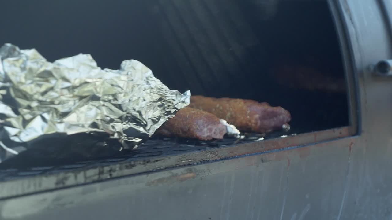 Uno chef posiziona costolette d'agnello speziate sulla griglia del barbecue per affumicare