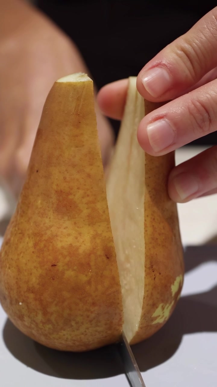 Persona che affetta una pera in cucina