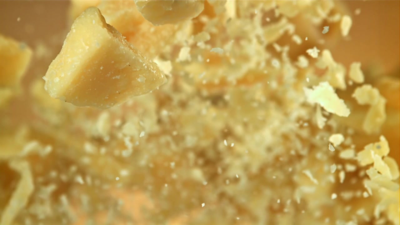 Primo piano di pezzi di formaggio Parmigiano che cadono al rallentatore