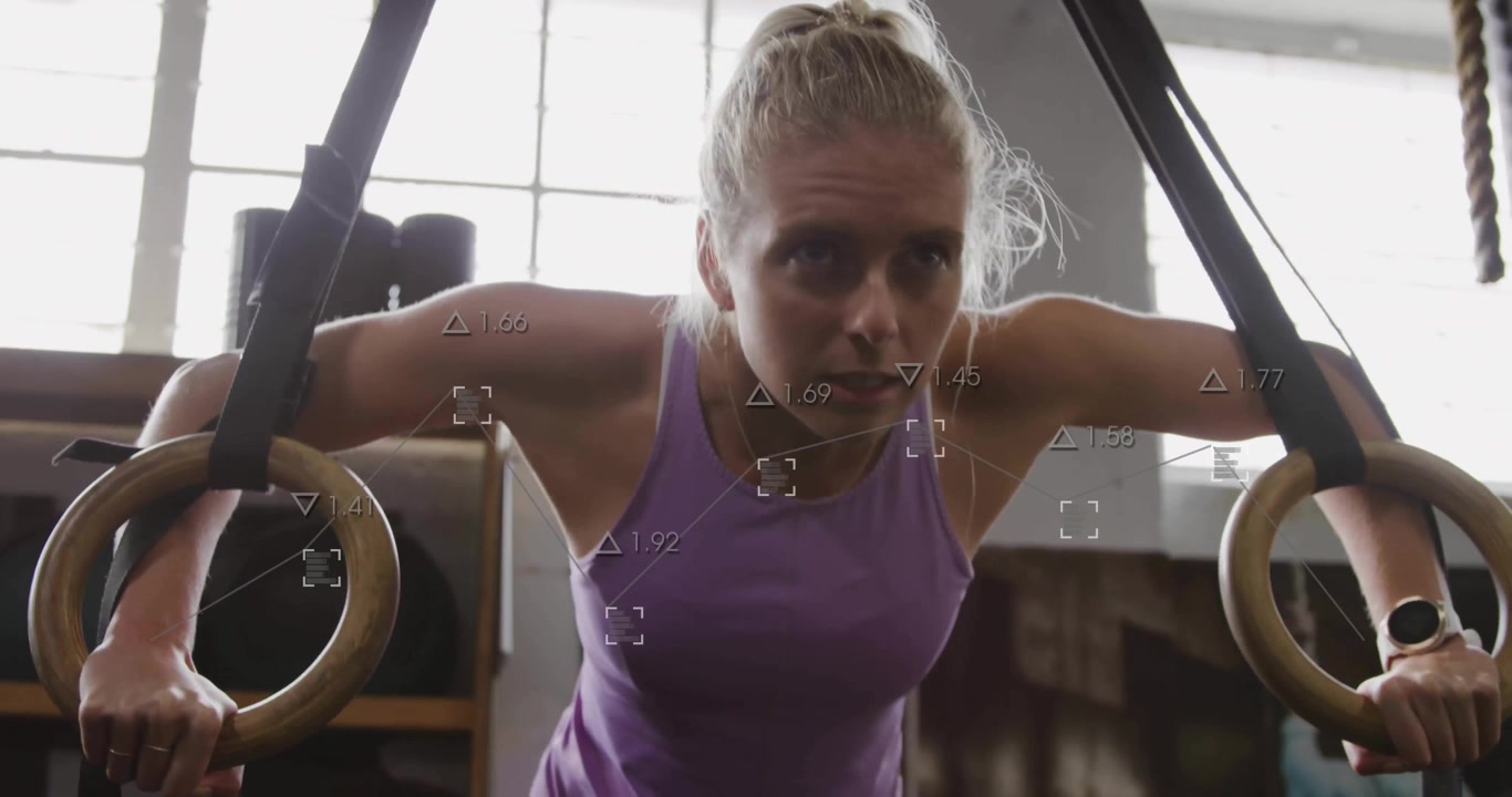 Atletisk kvinna greppar träringar framför ett fönster och utför en dipssekvens för gymträning.