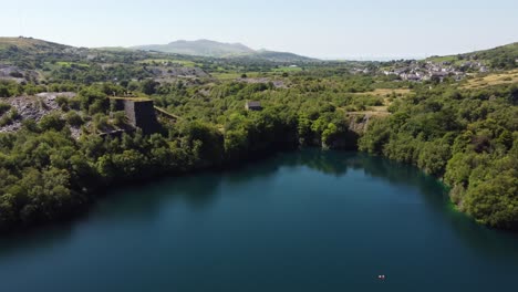 aerial view welsh woodland valley slate mining shaft and snowdonia mountains descent towards quarry lake