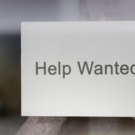 Employee-Hangs-On-The-Door-Ad-Help-Wanted