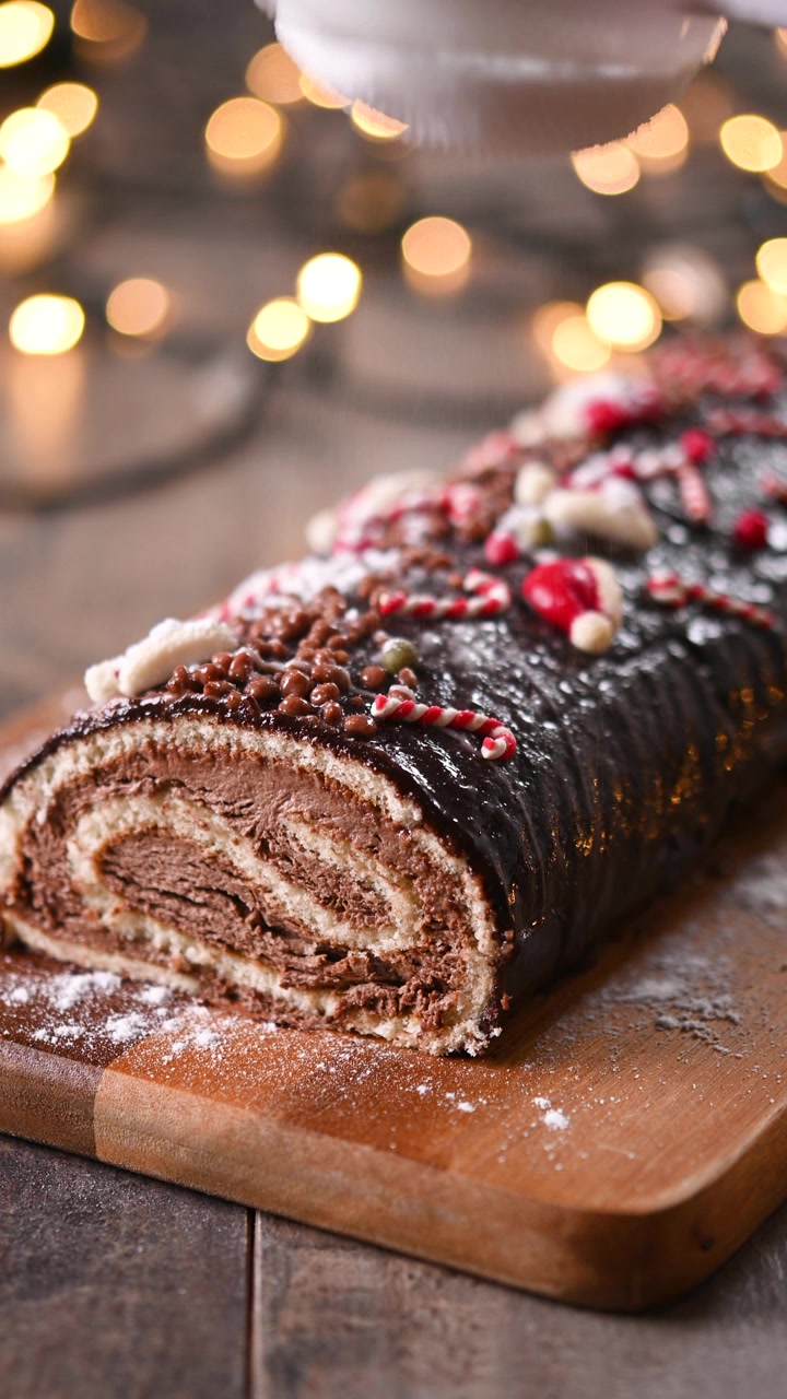 Bir Noel kütük pastasının üzerine pudra şekeri serpmek